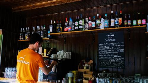 un homme debout derrière un bar avec des bouteilles d'alcool dans l'établissement Camping maeva Respire La Vallée Heureuse, à Orgon
