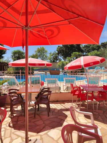 een groep tafels en stoelen met parasols naast een zwembad bij Bungalow de 2 chambres avec piscine partagee et terrasse amenagee a La Baule Escoublac in Saint-André-des-Eaux