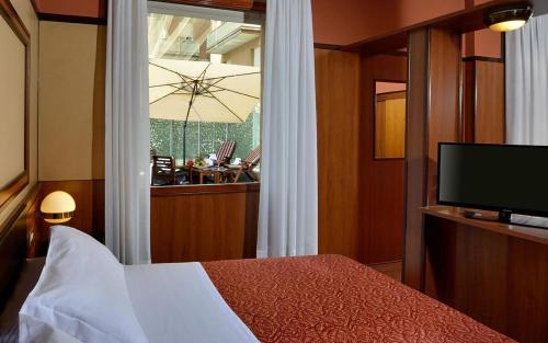 a bedroom with a bed and a window with a television at Grand Hotel Elite in Bologna