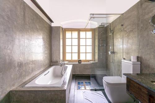 a bathroom with a tub and a toilet and a sink at Simpson's Forest Hotel in Kandy