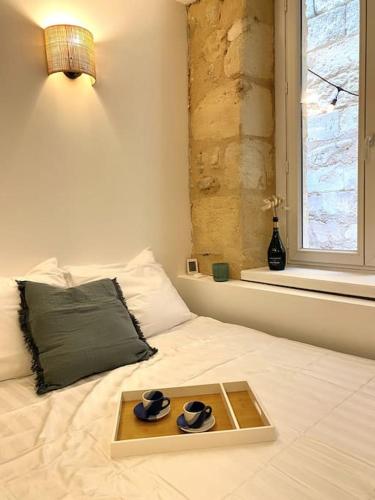 un plateau avec deux chapeaux sur un lit avec une fenêtre dans l'établissement Studio Bordelais avec terrasse, à Bordeaux