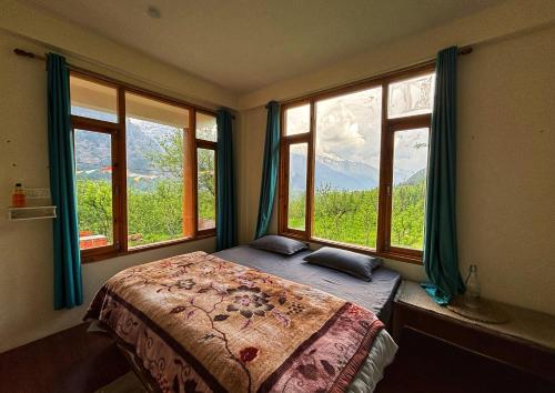 a bedroom with a bed and windows with a view at Kihala Homestay in Manāli