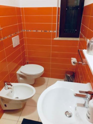 an orange bathroom with a toilet and a sink at Pit Lane AFFITTACAMERE in Offida