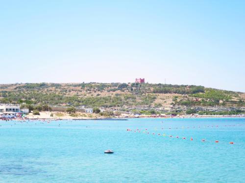 a large body of water with a beach in the background at Seafront apartment Terrace, lounger & Panoramic ocean views in Mellieħa