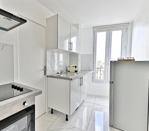 La cuisine blanche est équipée d'un évier et d'un réfrigérateur. dans l'établissement Appartement moderne proche Paris - Gagny, à Gagny