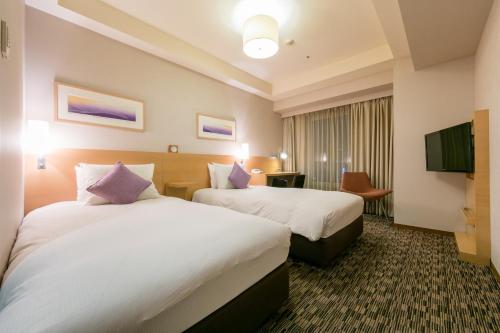 札幌市にあるホテルリソルトリニティ札幌のベッド2台とテレビが備わるホテルルームです。