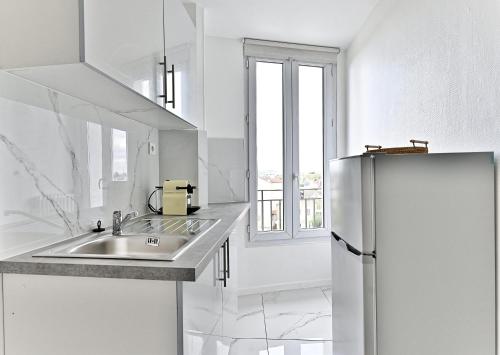 a white kitchen with a sink and a refrigerator at Appartement moderne proche Paris - Gagny in Gagny
