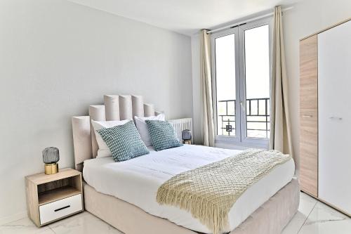 a white bedroom with a large bed and a window at Appartement moderne proche Paris - Gagny in Gagny