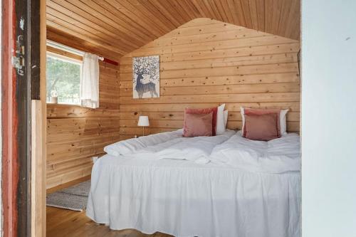 ein Schlafzimmer mit einem Bett in einer Holzhütte in der Unterkunft Cosy Cottages Close To Water in Djurhamn