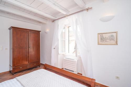 ein Schlafzimmer mit einem Holzschrank und einem Fenster in der Unterkunft FORTUNATA Apartment in Dubrovnik
