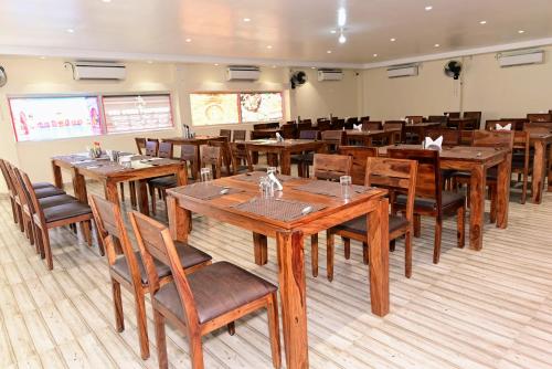 una sala da pranzo con tavoli e sedie in legno di The Byke Niranjana a Gaya