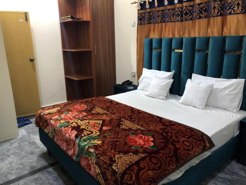 een slaapkamer met een groot bed met een blauw hoofdeinde bij Hotel Royal inn in Lahore