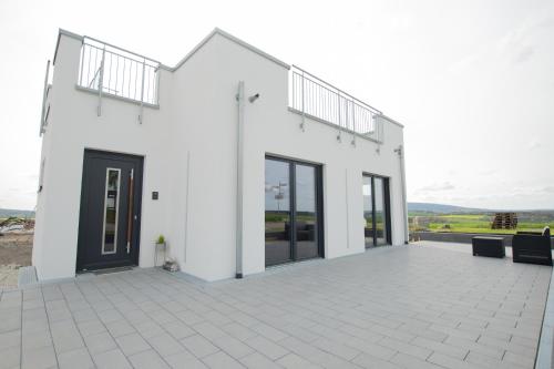 a white house with glass doors and a patio at Moderne Wohnung mit Panorama in Schneppenbach