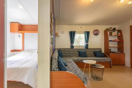 une pièce avec un canapé, un lit et une table dans l'établissement Mobilhome Mh 100 La Tremblade, à La Tremblade