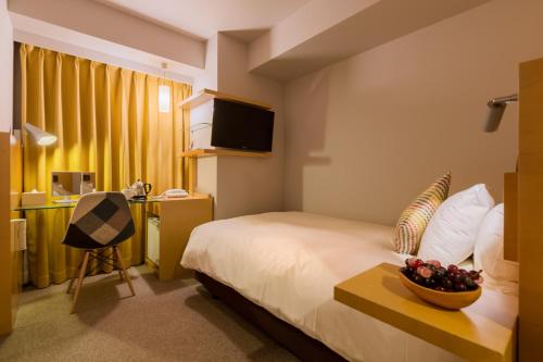a hotel room with a bed and a bowl of fruit on a table at Hotel Resol Trinity Sapporo in Sapporo