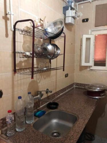 um balcão de cozinha com um lavatório e algumas garrafas de água em شقة بدمياط الجديدة مناطق هادئة em Dumyat al Jadidah