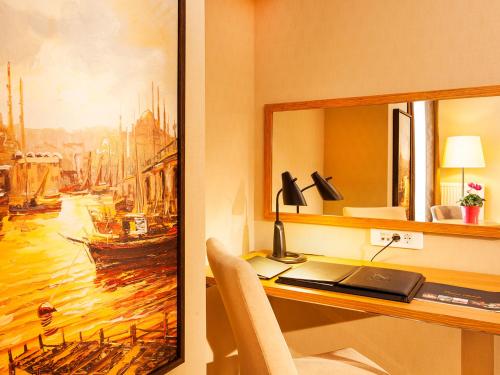 a desk with a laptop and a painting on the wall at Nidya Hotel Esenyurt in Istanbul