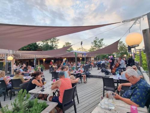 un groupe de personnes assises à des tables sur un patio dans l'établissement Camping Le Couriou - Maeva, à Recoubeau-Jansac