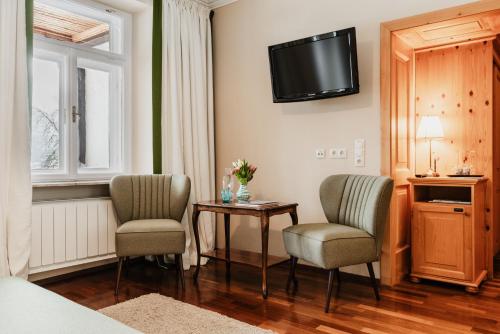 a room with two chairs and a table and a tv at Landhaus Koller in Gosau