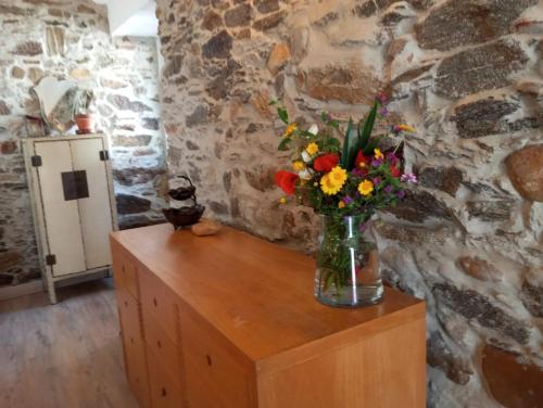 a vase of flowers sitting on top of a wooden cabinet at Casa das Mouriscas in Casalão