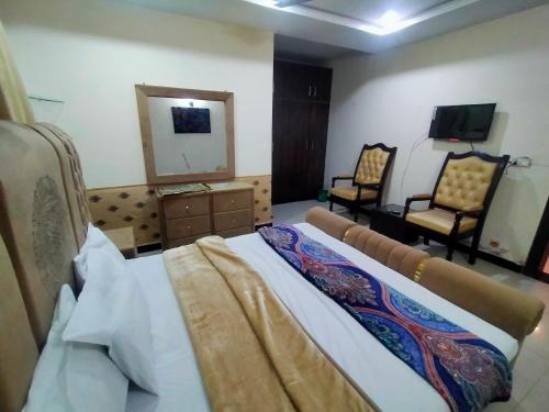 a room with a bed and two chairs and a mirror at Peridot Vacation Inn, Bahria in Islamabad
