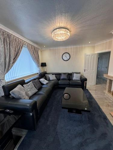 a living room with a black leather couch and a clock at 230 Councillor Lane in Cheadle