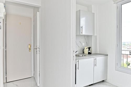une cuisine blanche avec des armoires blanches et un évier dans l'établissement Serenity spot at Gagny - Near Paris, à Gagny