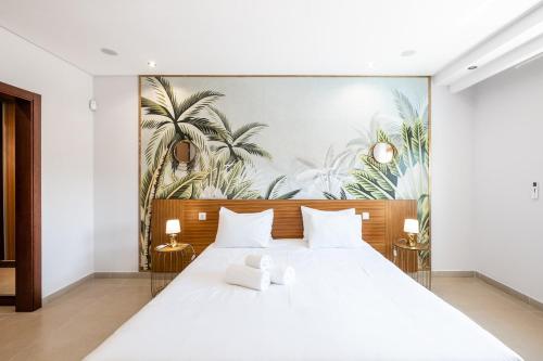 1 dormitorio con 1 cama blanca grande y un mural de palmeras en Villa Orada, en Albufeira