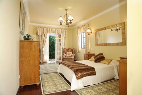 - une chambre avec un lit, un miroir et une chaise dans l'établissement Villa Jumar, à Albufeira