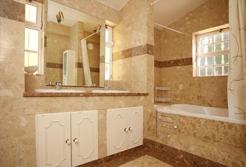 a bathroom with a tub and a sink and a mirror at Villa Jumar in Albufeira