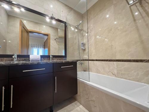 uma casa de banho com uma banheira, um lavatório e um espelho. em Light House Luxury Villa em Albufeira