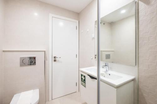 La salle de bains blanche est pourvue d'un lavabo et d'un miroir. dans l'établissement Marina Design T1, à Albufeira