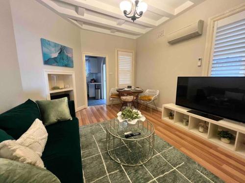 a living room with a green couch and a flat screen tv at Green Stays in Sydney