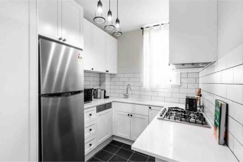 a kitchen with white cabinets and a stainless steel refrigerator at Green Stays in Sydney