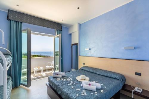 una camera blu con un letto e un balcone di Jonico Hotel a Torre San Giovanni Ugento