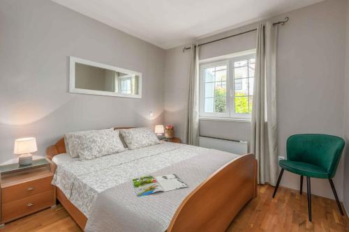a bedroom with a bed and a green chair at Apartment in Funtana/Istrien 31340 in Funtana