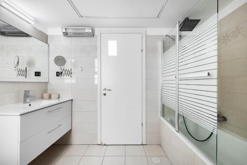 a white bathroom with a shower and a glass door at Ocean View Oasis with Balcony for families in Ashdod