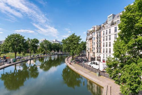 パリにあるティムホテル ガル ドゥ レスト（旧 ア ラ ヴィラ サン マルタン）の建物や木々が並ぶ都市の川