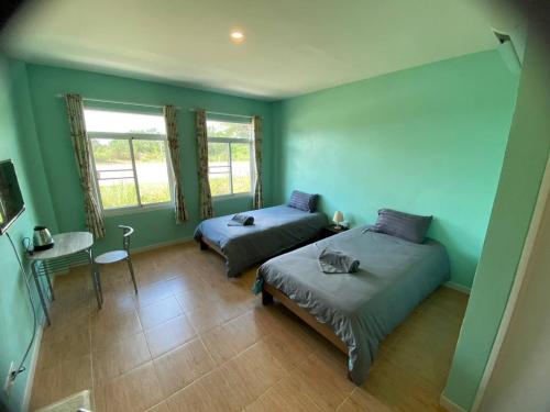 two beds in a room with green walls at โรงแรมบ้านสวนวินเทจ in Ban Nam Mong