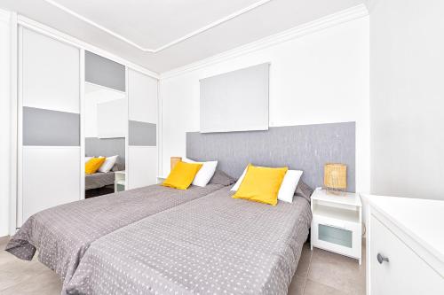 um quarto com uma cama com duas almofadas amarelas em Apartamento con vistas al mar em Arinaga