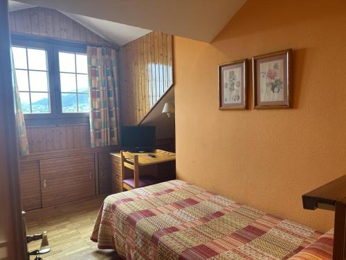 a bedroom with a bed and a desk and a window at Hosteria Gelin de Gajano in Gajano