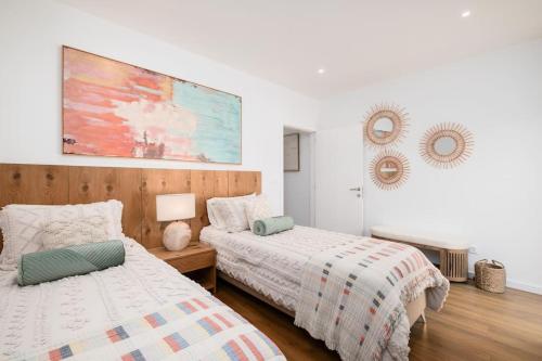 una camera da letto con due letti e un dipinto sul muro di Quinta do Refúgio a Rabo de Peixe