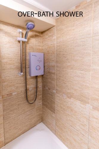 a shower in a bathroom with a shower head at Looe Self Catering in Looe