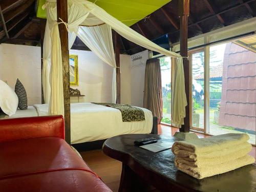 a bedroom with a bed and a table with a couch at Tunjung Sari Villa Bedugul in Bedugul