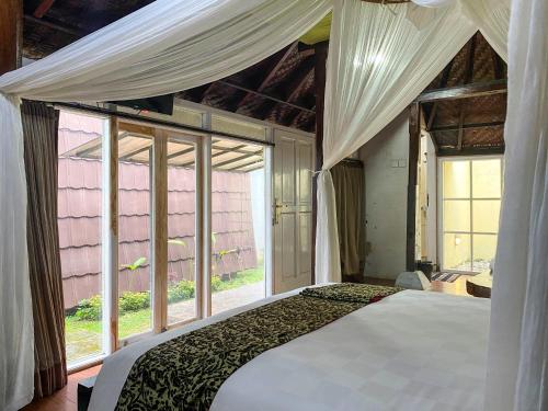 a bedroom with a bed and a large window at Tunjung Sari Villa Bedugul in Bedugul