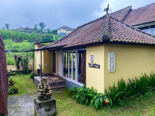 a small yellow house with a statue on the roof at Tunjung Sari Villa Bedugul in Bedugul