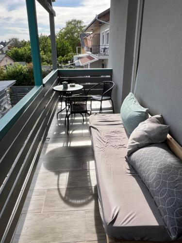 a balcony with a bed and a table and chairs at Szarkafészek in Keszthely