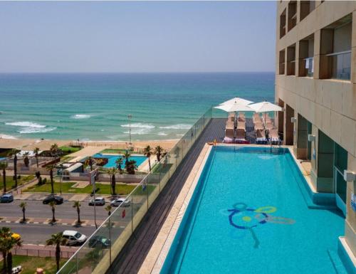 a swimming pool on the side of a building with the ocean at GO to apartments in Leonardo in Bat Yam
