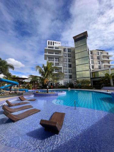 a swimming pool with lounge chairs in front of a building at Winrich Hotel in Lapu Lapu City