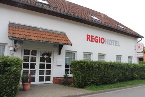 a white building with a red rico hotel sign on it at REGIOHOTEL Aparthotel Wernigerode in Wernigerode